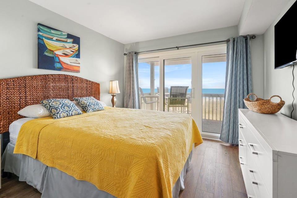 Bedroom with yellow bedding and balcony doors to the ocean view at Island Dunes A2, Ocean Drive