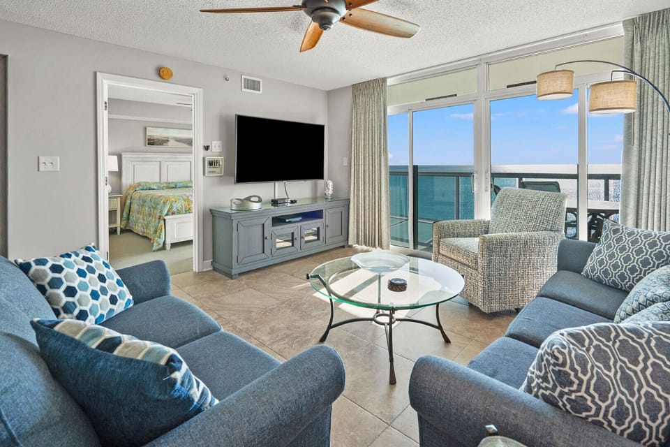 Blue sectional and balcony doors framing the ocean at Laguna Keyes 909, a 3-bedroom Cherry Grove condo
