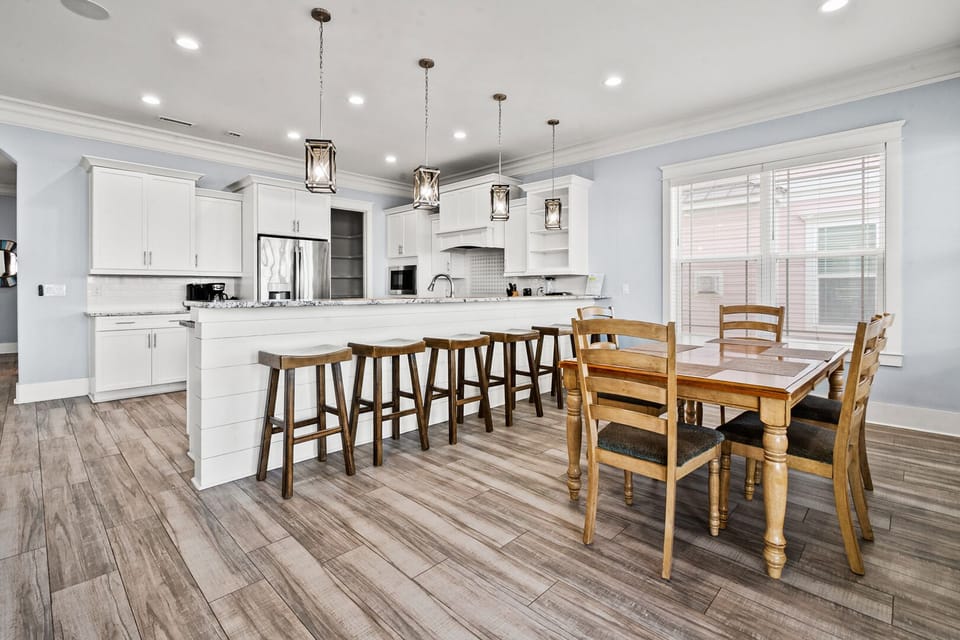 Island bar stools and a dining table below pendant lights at Ocean Current, a Cherry Grove vacation rental