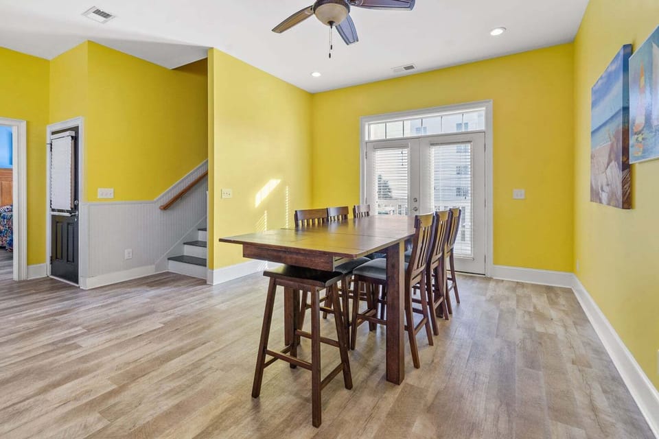 Dining table for six beside tall windows at A Perfect Escape, a 6-bedroom home in Cherry Grove, North Myrtle Beach