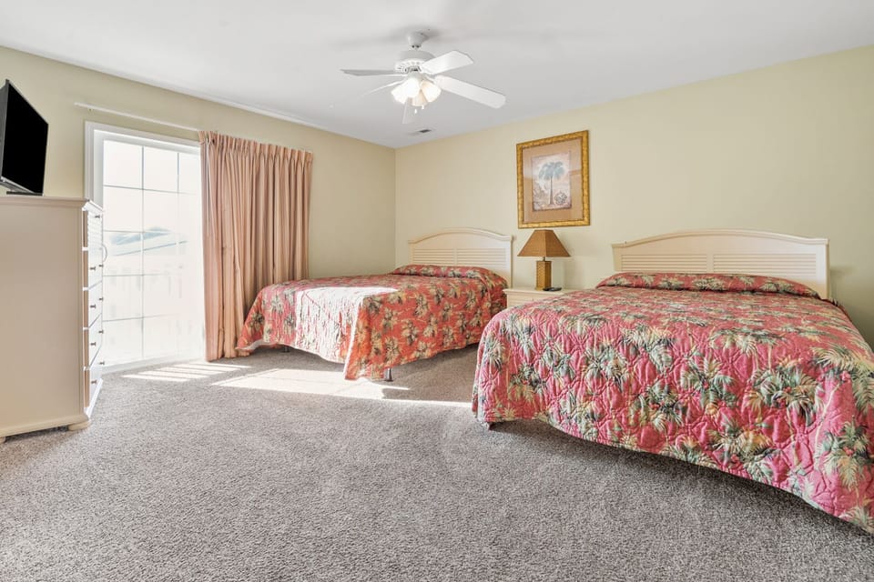 Beds with pink floral spreads at Admirals Quarters B, an 8-bedroom Cherry Grove rental
