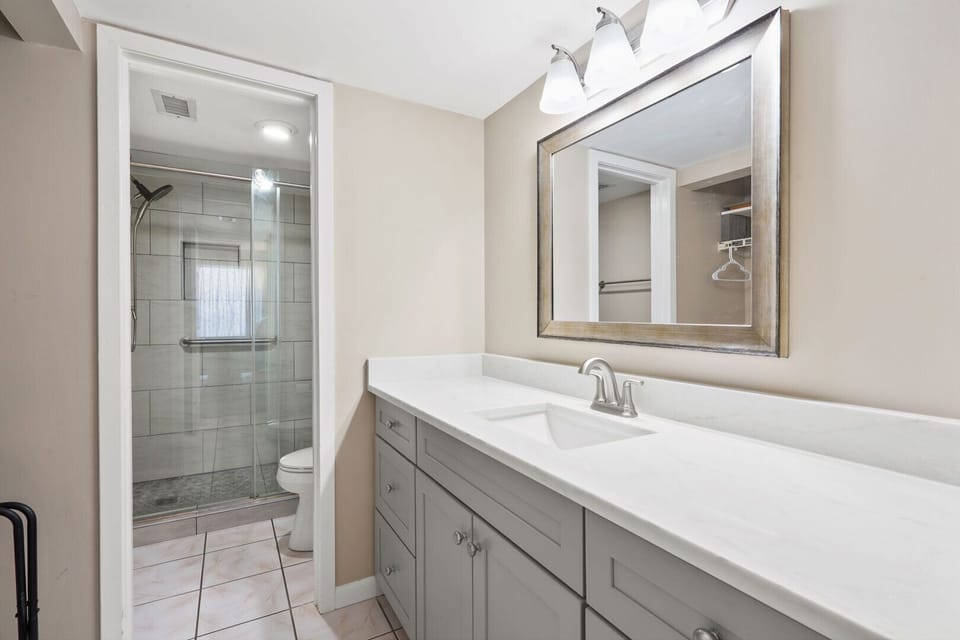Bathroom with a walk-in shower, wide mirror and vanity at Windemere 902 in Ocean Drive, North Myrtle Beach