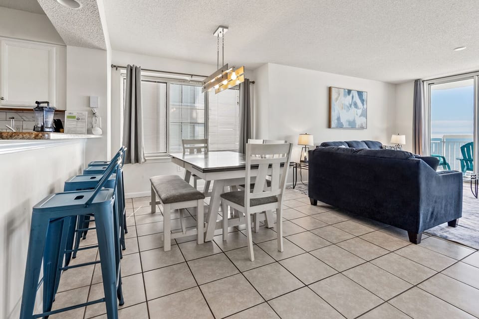 Dining table and bar stools beside the living area at Crescent Shores 706, a 4-bedroom Crescent Beach condo rental