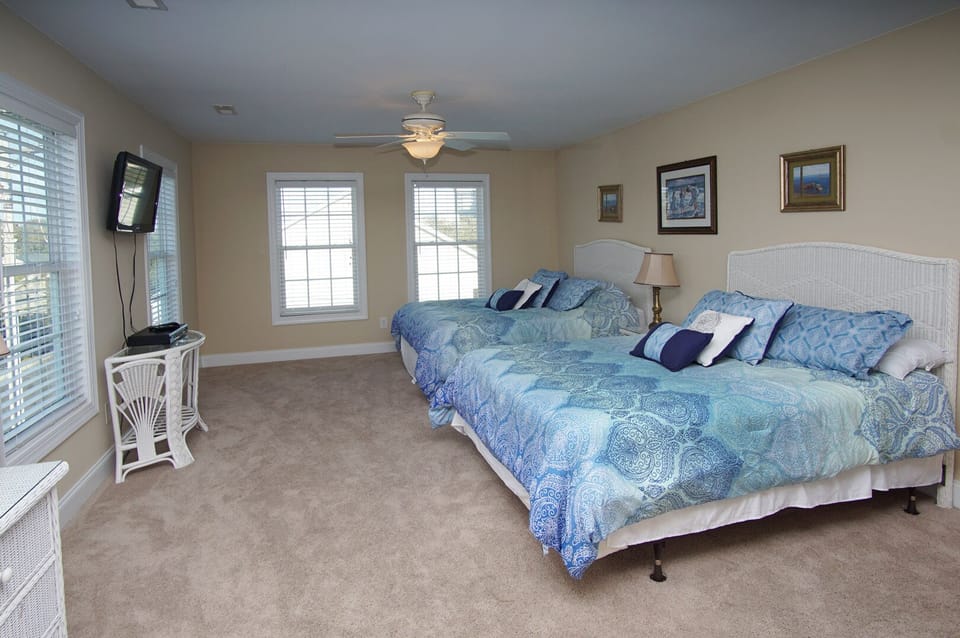 Bedroom with two beds, blue bedding and a wall-mounted TV at West Winds II, a 5-bedroom Crescent Beach rental