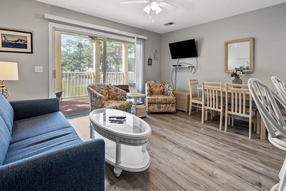 Open living and dining space with a mounted TV at Tilghman Shores H2, a 1-bedroom Cherry Grove condo rental