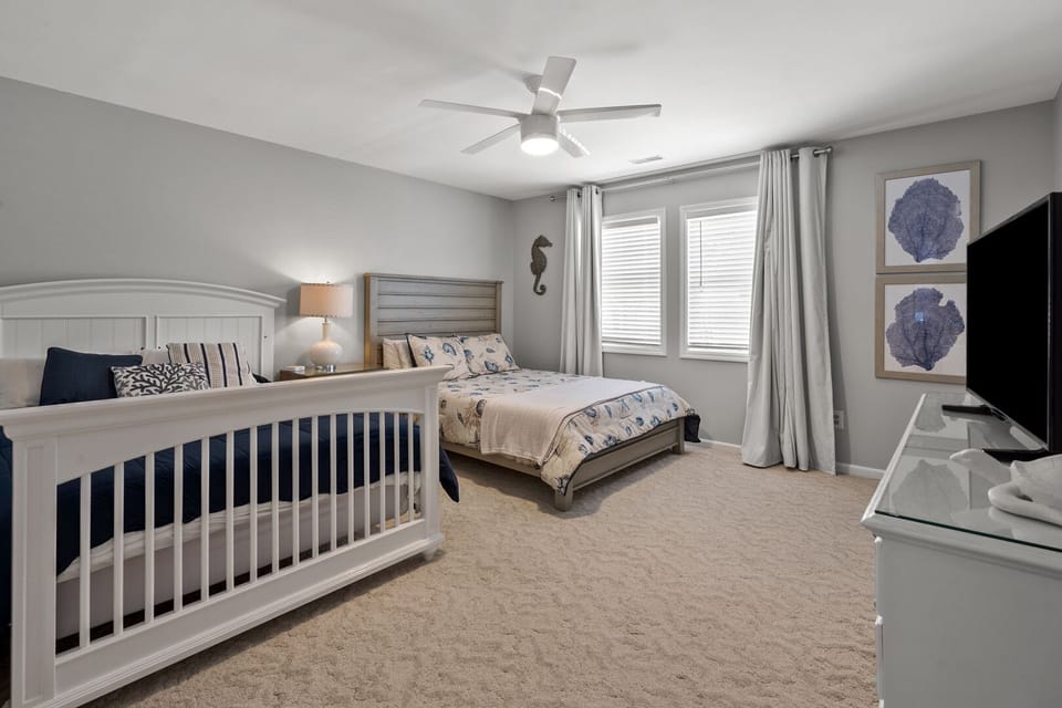 Two beds, a mounted TV and seashell decor in a bedroom at The Lazy Turtle in the Ocean Drive section