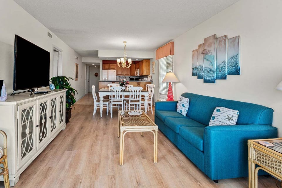 Sectional sofa and a white dining table under a chandelier at Surf Villas II C1, an Ocean Drive vacation rental