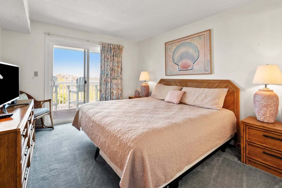 Bedroom with a bed, dresser and sliding door to the balcony at Surf Villas II C1 on Ocean Drive