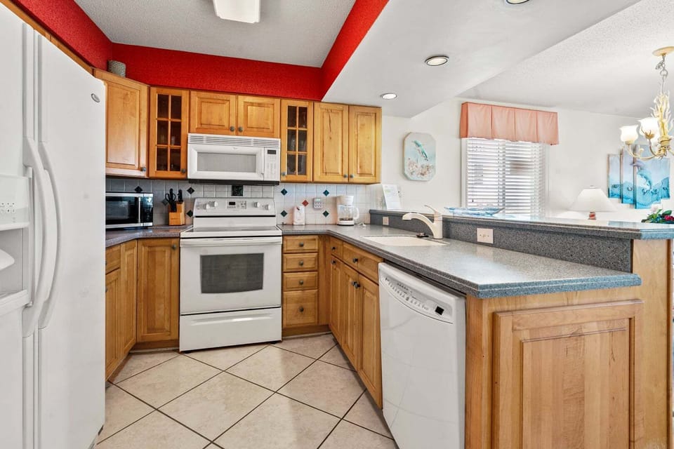 Light cabinets and a red accent wall in the kitchen at Surf Villas II C1, an Ocean Drive vacation rental