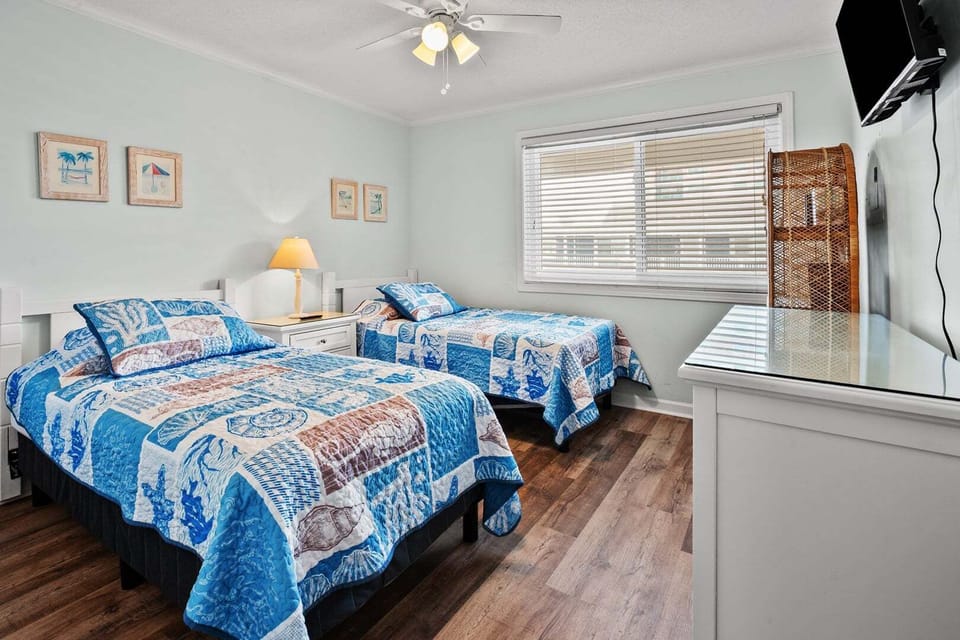 Two beds with blue quilts and a wall-mounted TV at Summer Place C3 in Cherry Grove