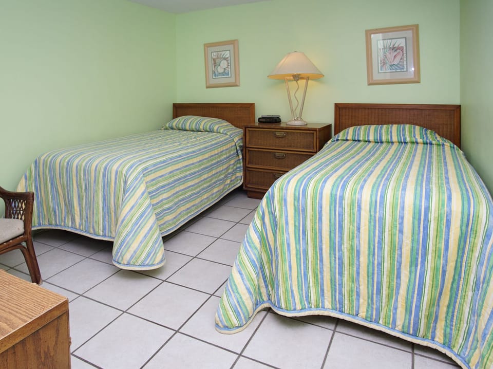 Two beds with striped bedding in a green-walled bedroom at Sea Castle 6D, a 3-bedroom Crescent Beach condo