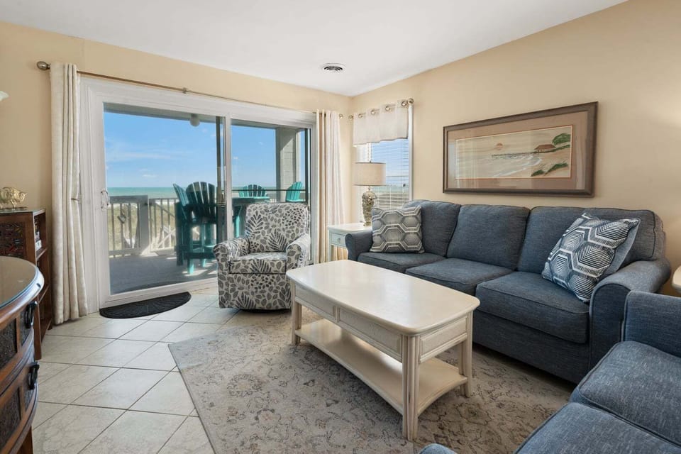 Blue sofa and armchair beside the balcony doors at Sand Trap Villas C1, Cherry Grove, North Myrtle Beach