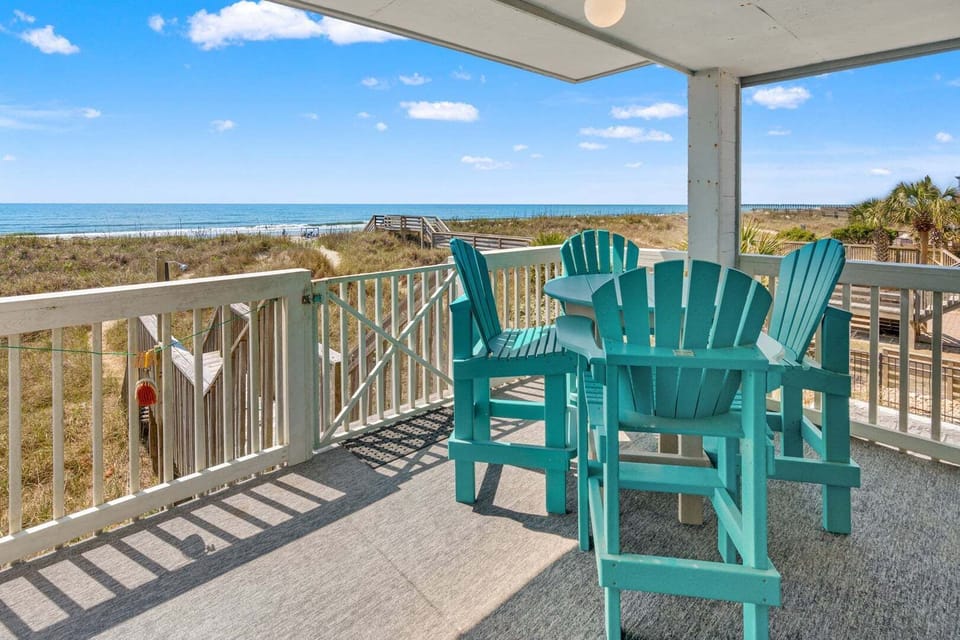 Porch with Adirondack chairs and a table facing the ocean at Sand Trap Villas C1, a 4-bedroom oceanfront rental