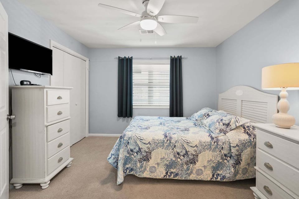 Blue and white bedroom with a wall TV, dresser and closet at Sand Trap Villas C1, Cherry Grove, North Myrtle Beach