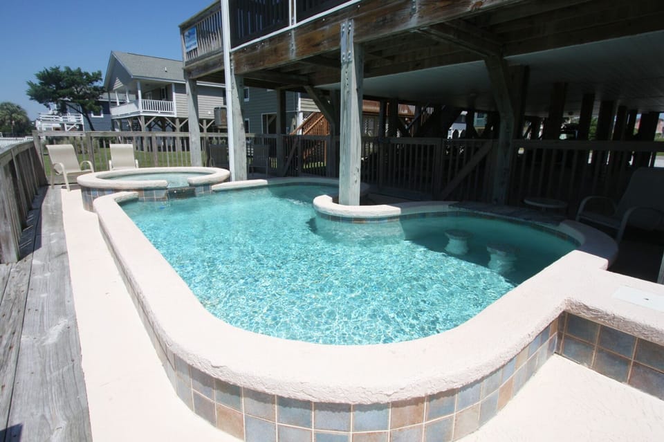 Fenced pool and hot tub with deck chairs at Cherry Delight, a 7-bedroom Cherry Grove vacation rental