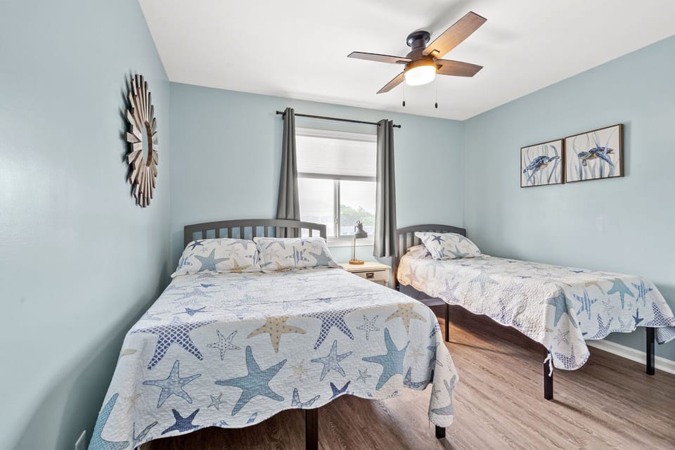 Starfish-patterned bedding on two beds beside a curtained window at Surf Villas II D3, Ocean Drive