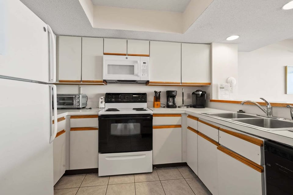 Kitchen with white cabinetry, full appliances and a double sink at Shoreham Towers II 2D, Crescent Beach