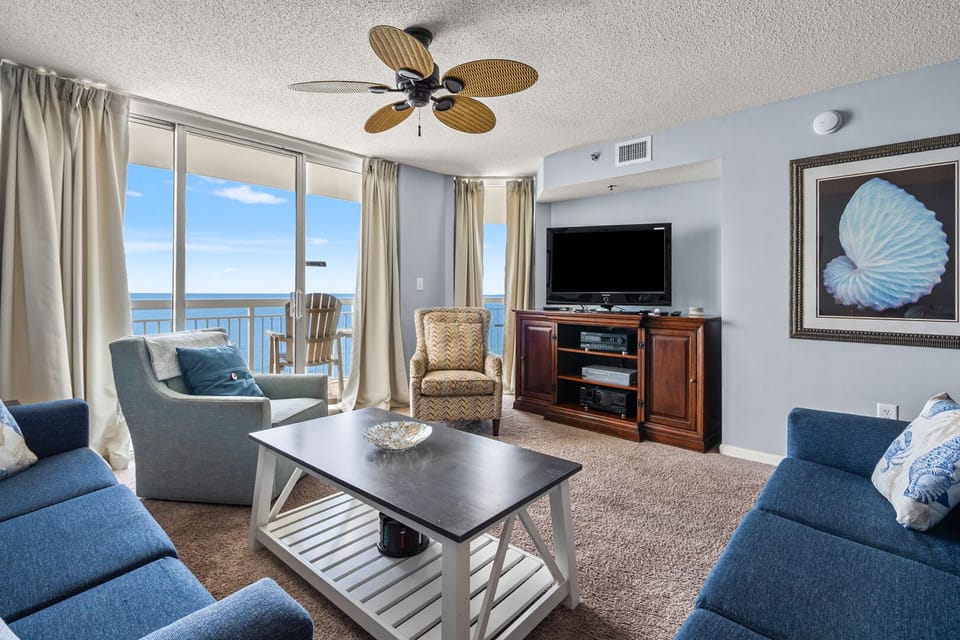 Sliding doors frame the ocean beside coastal art in the living area at Crescent Shores PH 1808