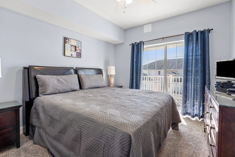 Bedroom with balcony access and a wall TV at Coconut Grove 404, an Ocean Drive beach house rental