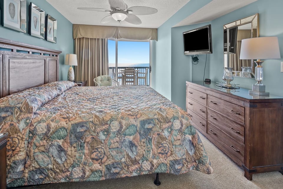 Bedroom with a wall TV and a sliding door to the ocean-view balcony at Ashworth 1103, Ocean Drive