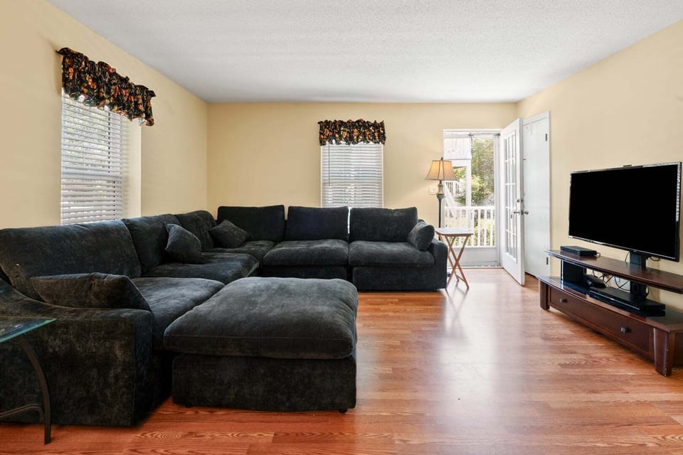 Living room with a sectional, TV and door to the porch at Blue Atlantic in the Ocean Drive section