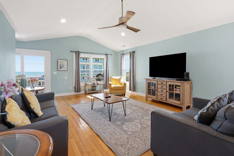 Sectional seating and a TV facing the ocean-view window at Beach Haven 1 in Cherry Grove