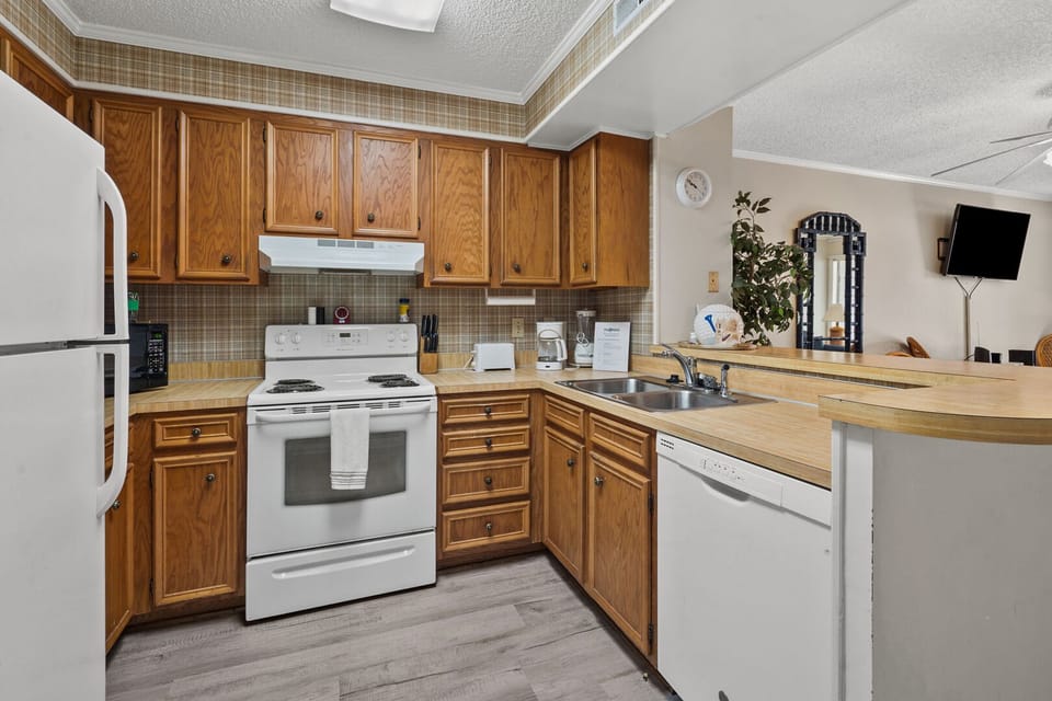 Kitchen with wood cabinetry and white appliances at Tilghman Beach & Racquet Club 140, Ocean Drive vacation rental