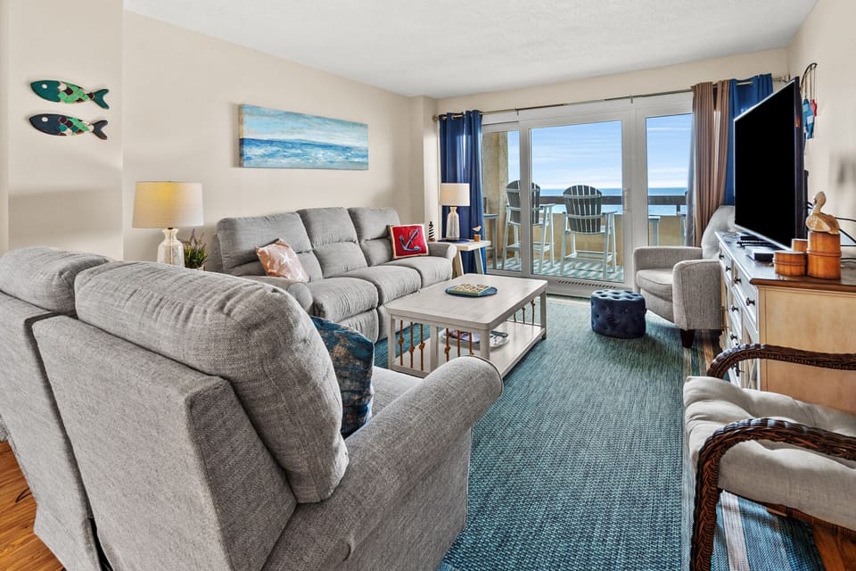 Living room with a sectional sofa and sliding doors to the ocean view at Sea Pointe 802 in Cherry Grove