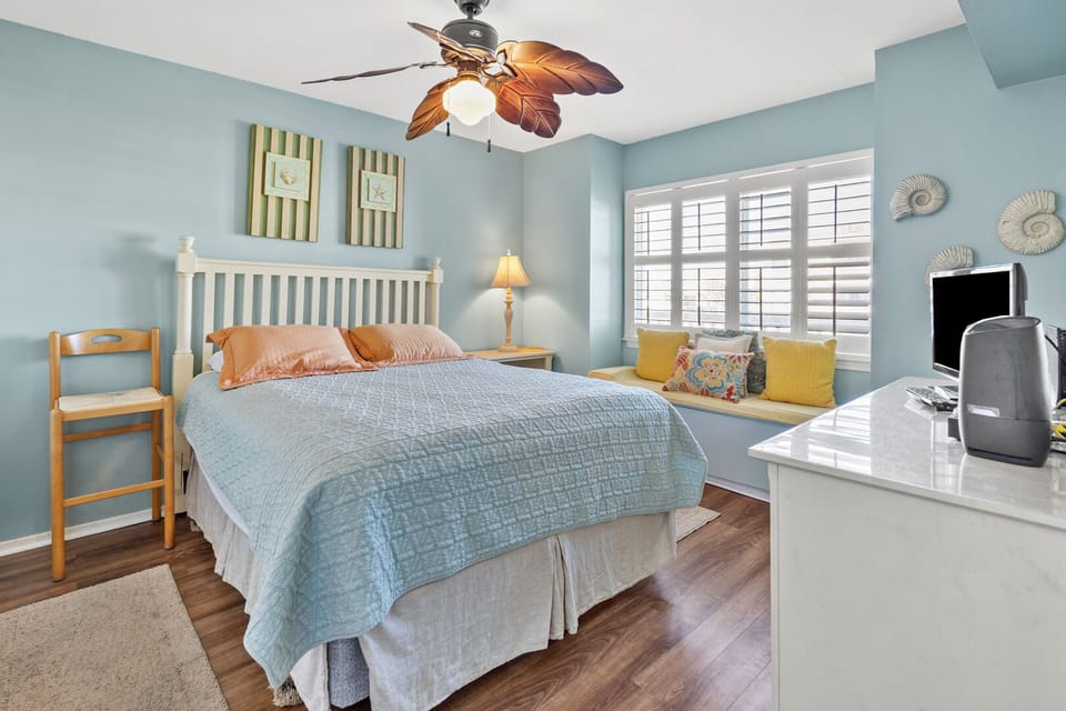 Bedroom with a cushioned window seat and blue quilt at Raintree Villas 1E, Cherry Grove vacation rental