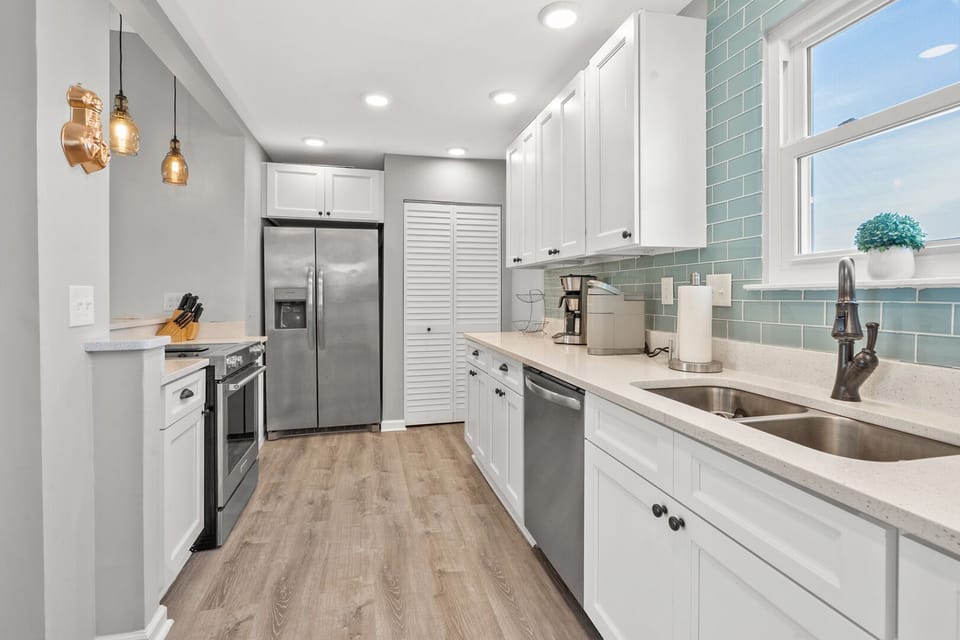 Bright kitchen with a wide refrigerator, sink and blue backsplash at Pelican's Perch in North Myrtle Beach