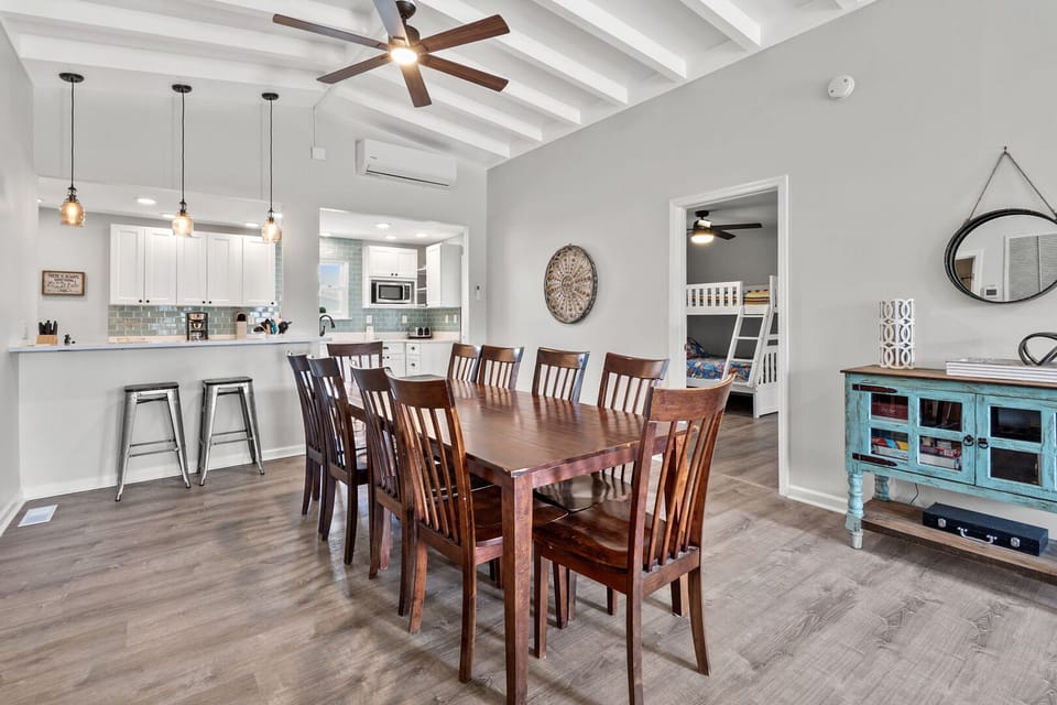 Dining table seating eight beside the kitchen bar at Pelican's Perch, a 4-bedroom Cherry Grove rental
