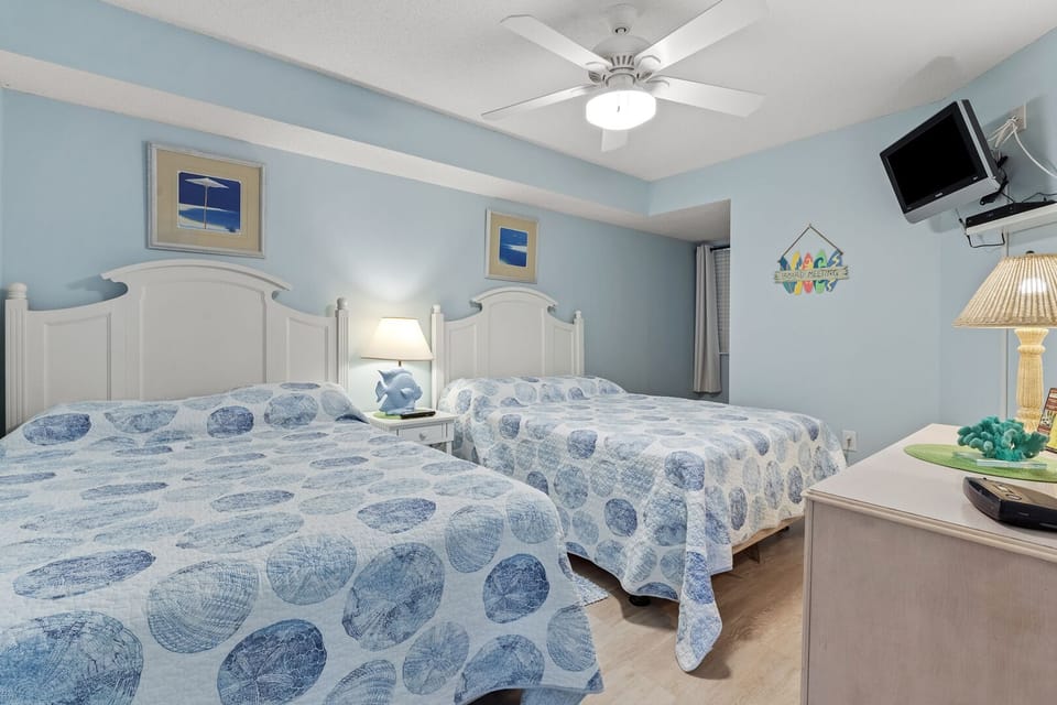 Two beds and a wall-mounted TV in a bedroom at North Shore Villas 701, a 4-bedroom Ocean Drive condo rental
