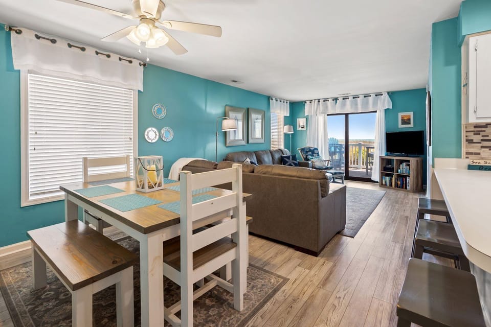 Dining table and living area share the balcony doors at Surf Villas I A1, a 3-bedroom Ocean Drive condo