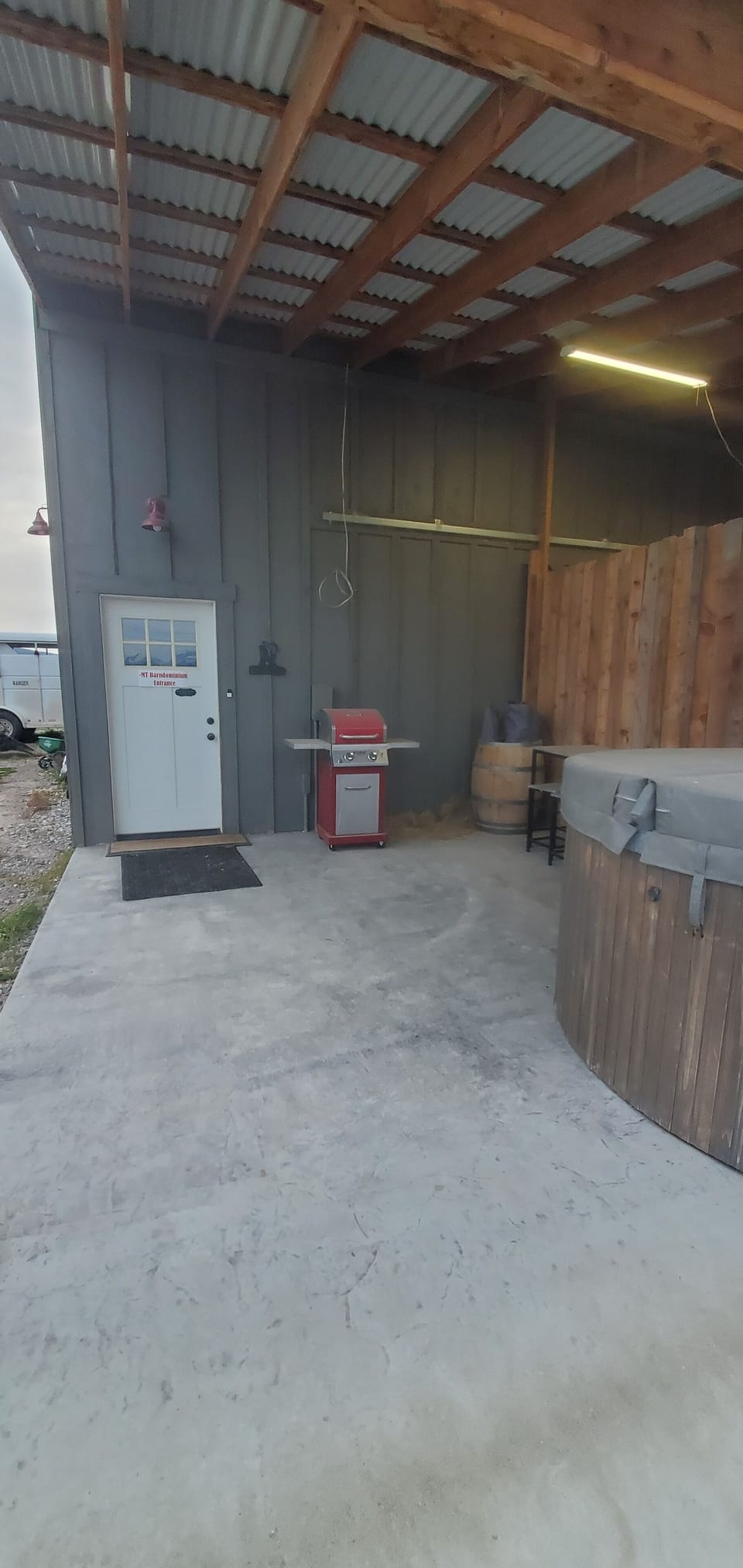 Outside patio with BBQ, hot tub, and some camp chairs.
