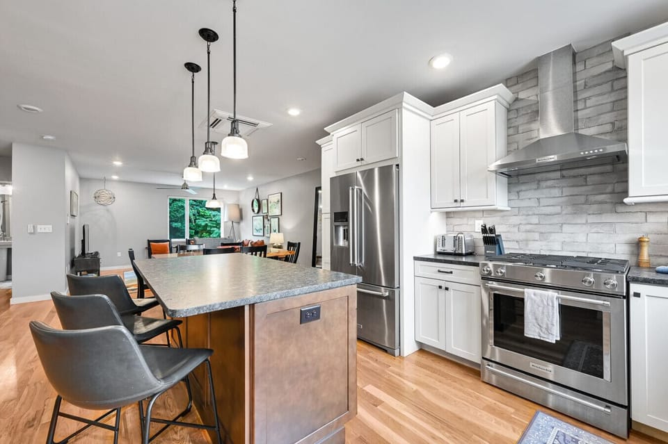 Stainless kitchen with island bar, gas range, and double door fridge