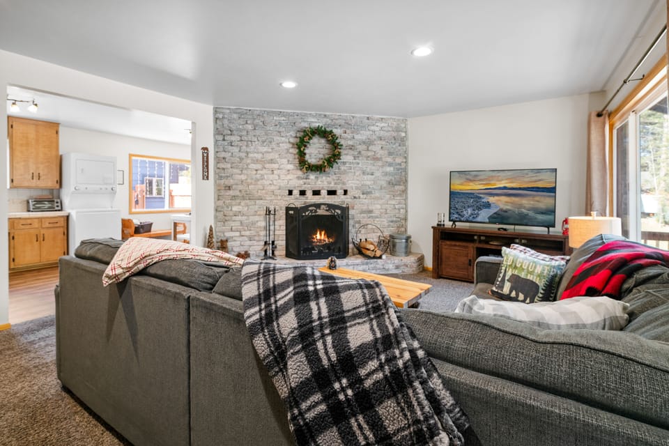 Living Room with wood burning fireplace, smart TV, large sectional couch.