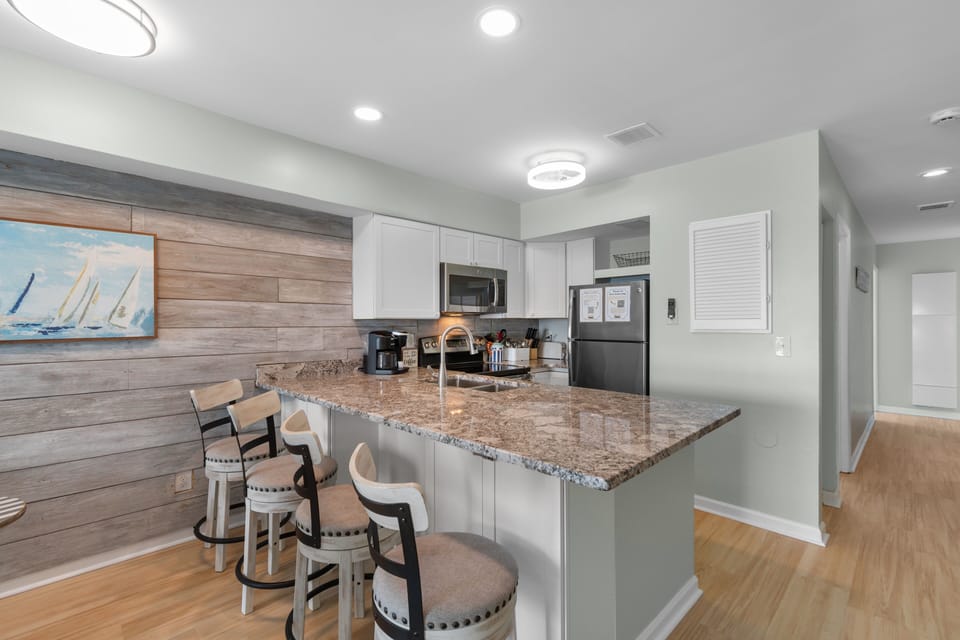 Gather around this bright kitchen featuring white cabinetry, and modern appliances perfect for preparing meals together during your stay.