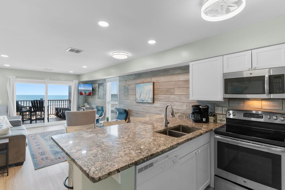 Your bright, coastal kitchen opens to a stunning sea-view balcony, where morning coffee and ocean breezes meet.