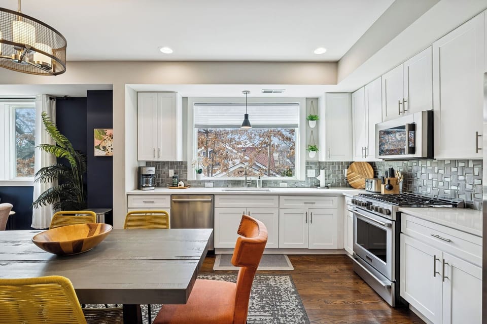 - Bright, modern kitchen with oversized window, stainless appliances & cheerful vibes - Gather around a bold dining table with eclectic chairs & playful textures - Perfect flow into the cozy living space, ideal for sharing meals & memories