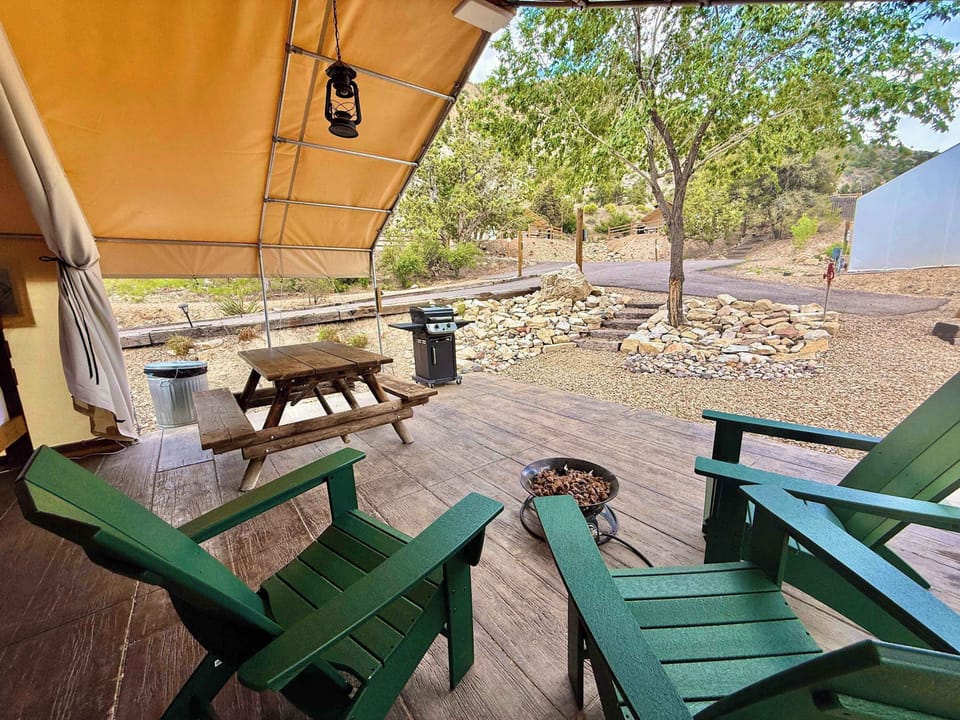 Covered patio at your glamping tent with outdoor seating, a fire pit, picnic table, and room to relax after a day exploring Zion National Park and Bryce Canyon.