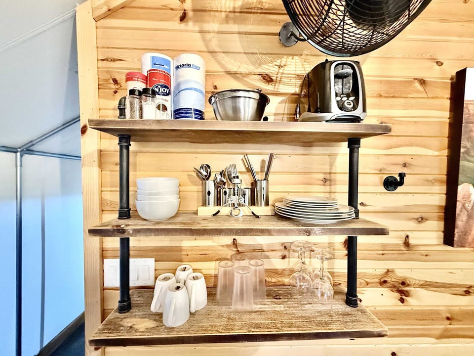Well-stocked kitchen area with kitchenware, hot plate, utensils, cookware, and essentials for preparing simple meals during your glamping stay.