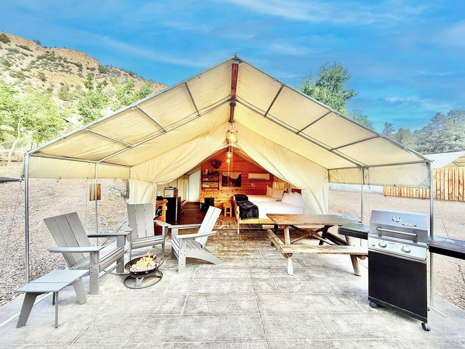 Covered patio at your glamping tent with outdoor seating, a fire pit, picnic table, and room to relax after a day exploring Zion National Park and Bryce Canyon.