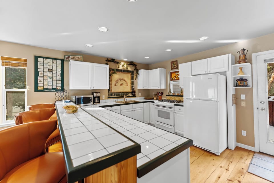 Your fully equipped kitchen awaits with white appliances, tile countertops, and cozy breakfast bar seating for memorable meal prep.
