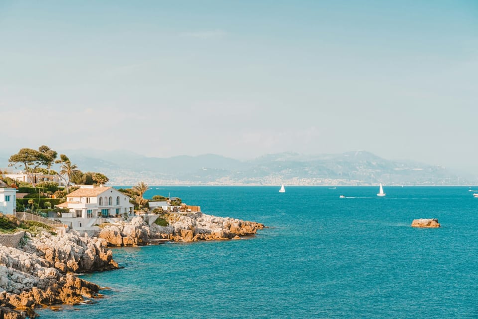 Low rocky promontory with white-rendered villas at the water's edge and turquoise Mediterranean sea at Antibes