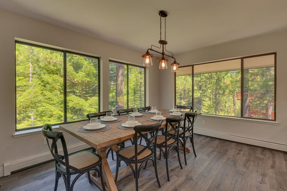 - Dining room with seating for eight guests  
- Surrounded by windows with forest mountain views  
- Rustic wood table and warm modern lighting