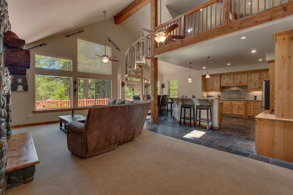 - Spacious living area with loft view  
- Open kitchen and stone fireplace  
- Spiral staircase adds rustic character