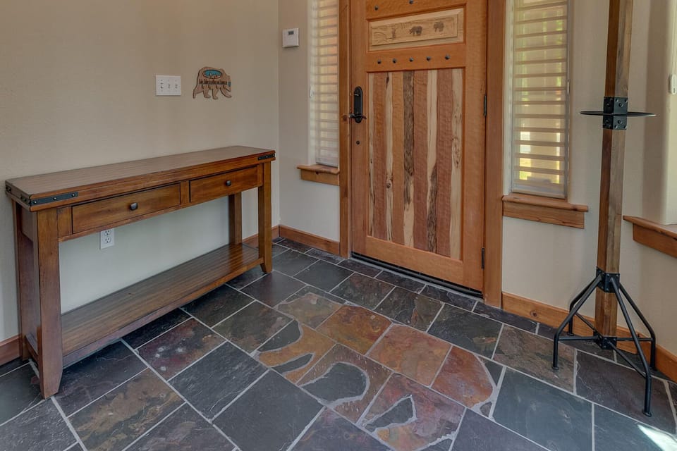 - Rustic entry door with wood detail  
- Stone tile flooring throughout  
- Welcoming cabin entrance