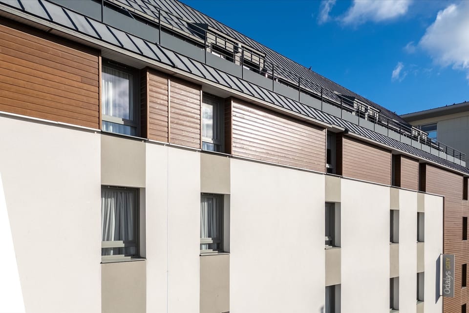 The building's clean lines and minimalistic façade highlight a blend of urban sophistication, with large windows allowing natural light to flood into the stylishly arranged apartments.