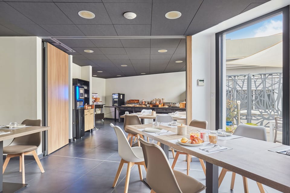 Indulge in a breakfast experience featuring a modern dining area filled with warm wood accents, sleek furnishings, and fresh pastries, inviting you to start your day in comfort and style.