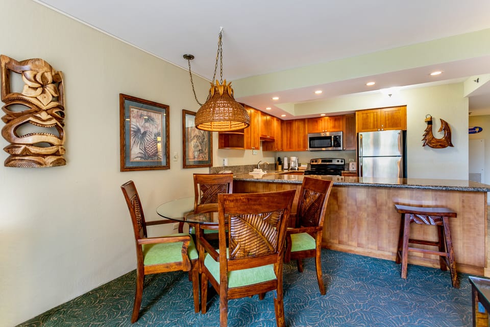 Your tropical-inspired retreat features a fully equipped kitchen with granite counters and stainless appliances, plus a dining area perfect for enjoying meals together. Warm wood tones and island-themed décor create a relaxed, vacation vibe.